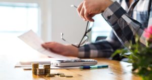 hands holding paper of table with money on top of it