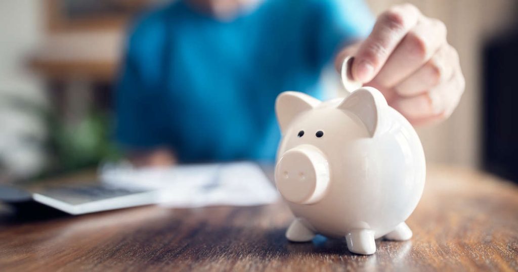 hand dropping coin in piggy bank
